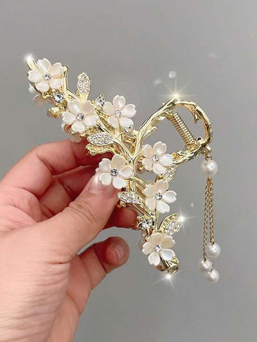 کلیپس موی زنانه فلزی طلایی طرح شکوفه، نمایش دادهشده در دست برای نشاندادن ابعاد و جزئیات واقعی محصول؛ وارداتین